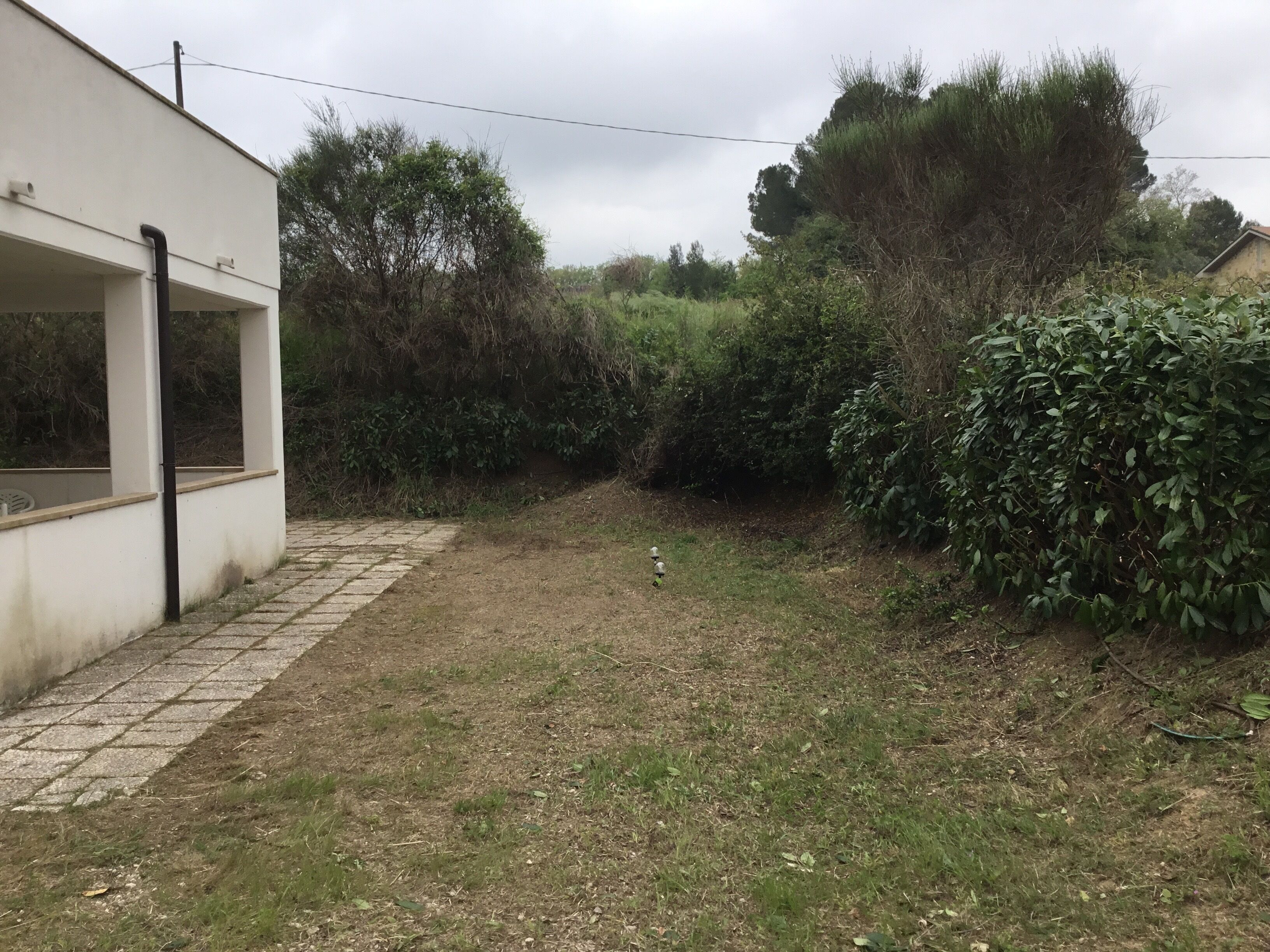 Un chemin pavé mène à un bâtiment blanc doté d’un porche abrité.