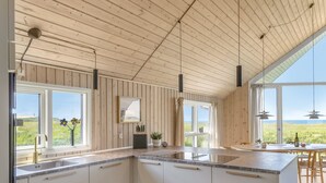A modern kitchen with wooden paneling, large windows, and a view of the outdoors. - "Tilje" - 80m from the sea by Interhome (Hjørring)