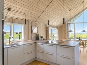 A modern kitchen with wooden paneling, large windows, and a view of the outdoors.