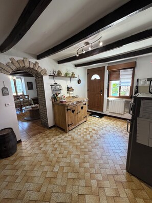 A rustic kitchen with a herringbone floor pattern, wooden cabinets, and a stone archway.