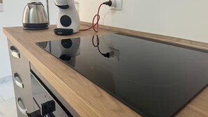 A kitchen with a black induction cooktop, a kettle, and a coffee maker on a wooden countertop. - Betta's House, the vacation home just a few kilometers from Taormina and Catania. (Sant'Agata li Battiati)