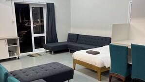 A modern, well-lit room with a bed, two sofas, a desk, and a chair. - 2 Double 3 Single  2 Sofa Beds Studio (Auckland)