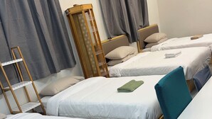 A hotel room with three single beds, a wooden ladder, a small table, and grey curtains. - 2 Double 3 Single  2 Sofa Beds Studio (Auckland)