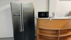 A stainless steel refrigerator with a digital control panel, a microwave, and a wooden countertop with a kettle. - 2 Double 3 Single  2 Sofa Beds Studio (Auckland)