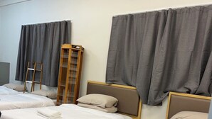 A hotel room with two single beds, a wooden desk, a small table, and a tall wooden cabinet. - 2 Double 3 Single  2 Sofa Beds Studio (Auckland)