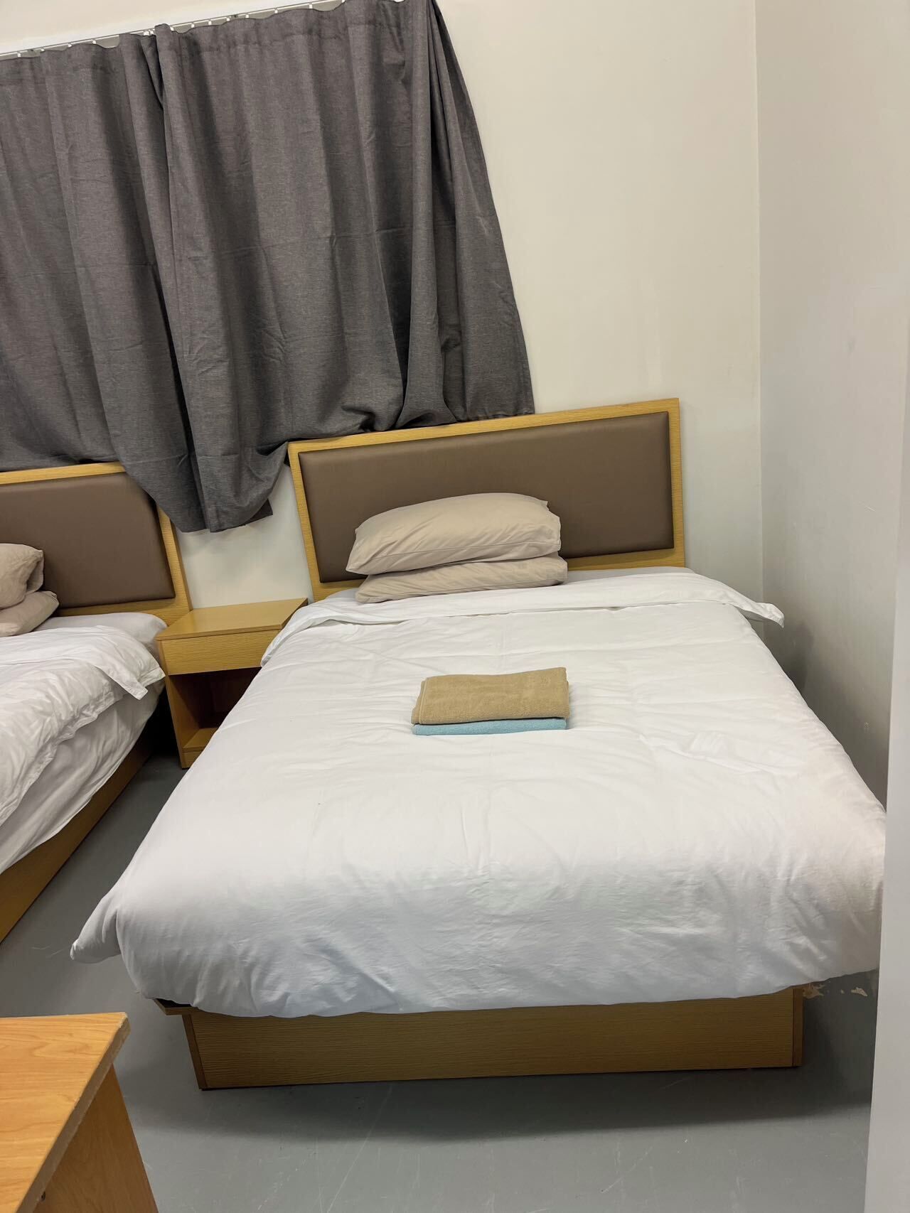 A single bed with a wooden frame and a headboard, accompanied by a nightstand.