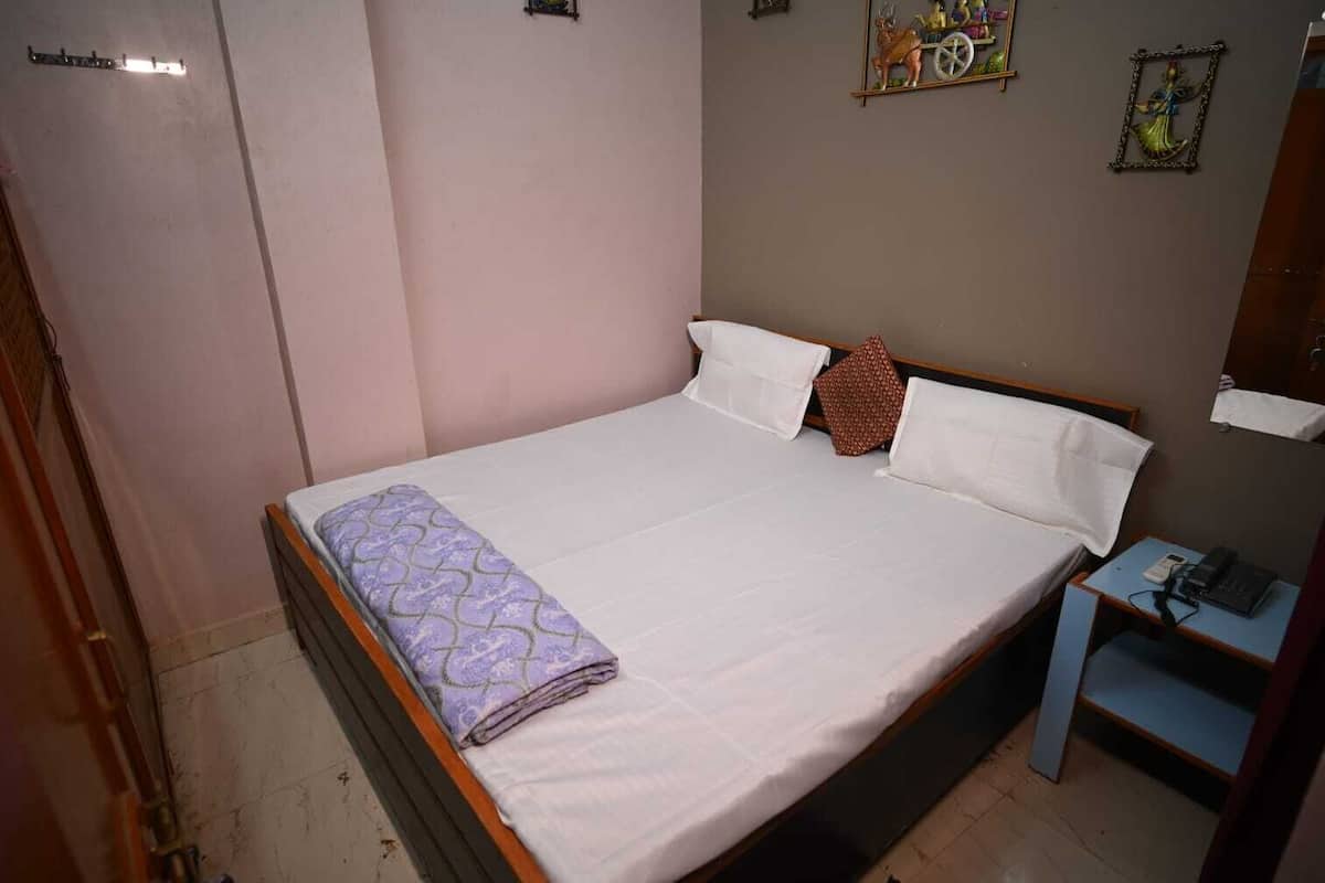 Un llit ben fet amb llençols estampats, una taula de nit amb un telèfon i una decoració penjada a la paret.