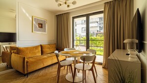 Una sala moderna con un sofá, una mesa de comedor, sillas y una televisión.