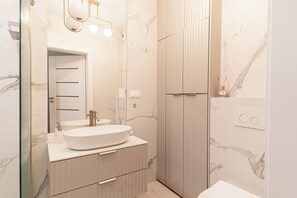 Casa de banho moderna com um espelho grande, uma sanita branca e área de duche.