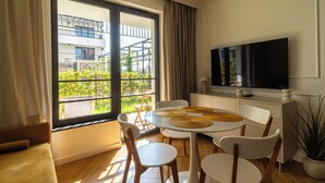 Una sala de estar moderna con comedor, ventanas amplias, televisor de pantalla plana y una planta en maceta.