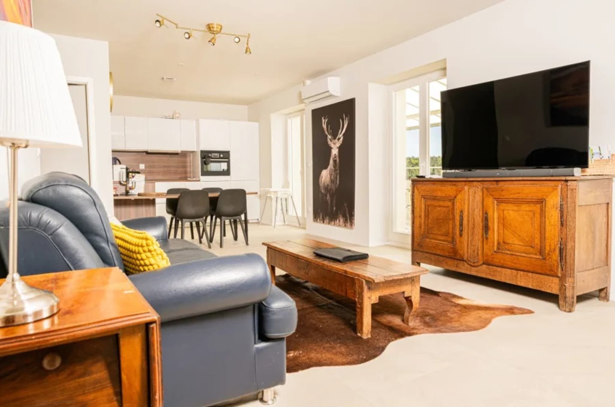 Una sala de estar moderna con un sofá, una mesa de centro y un televisor sobre un mueble de madera.