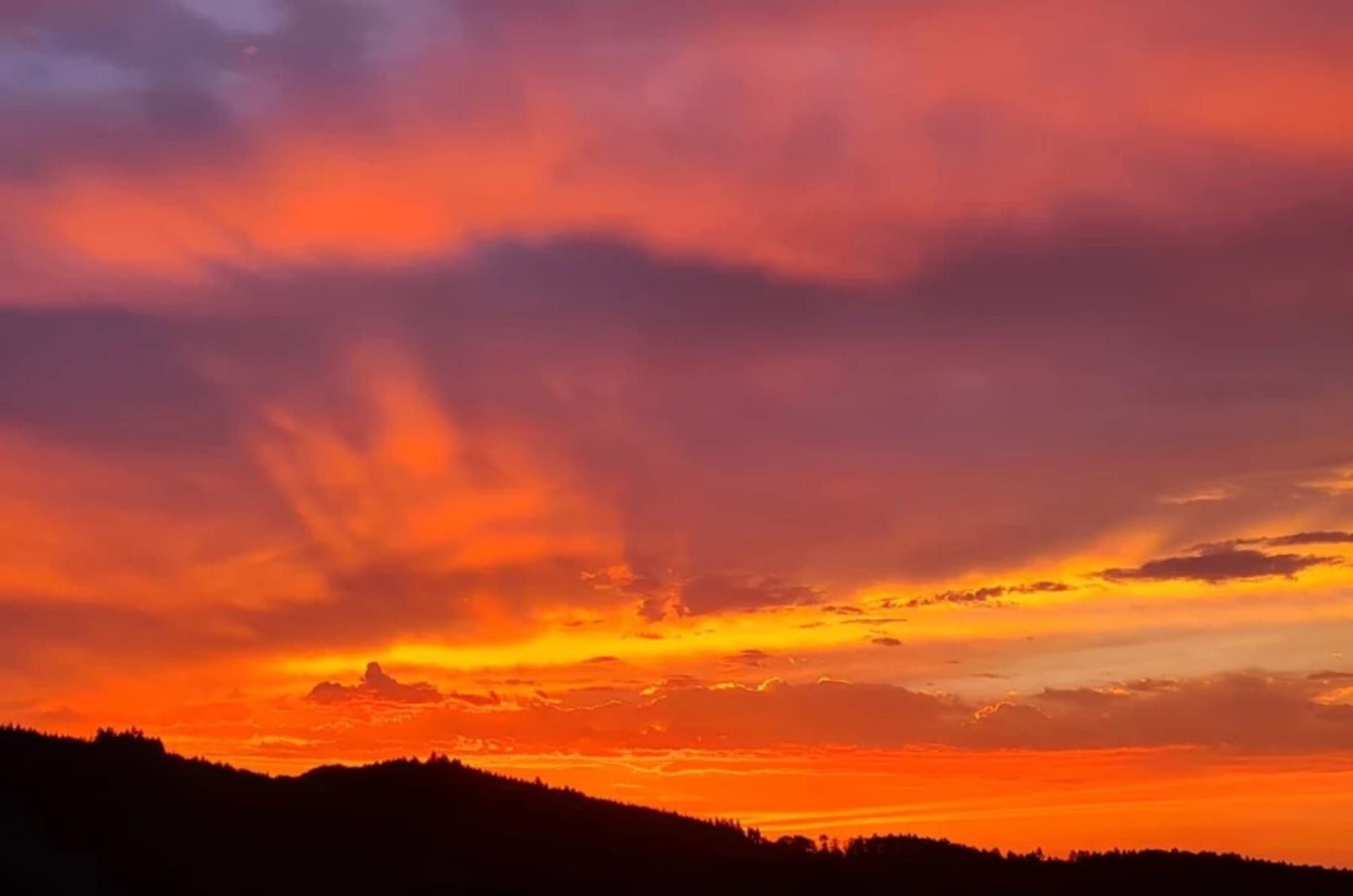 Un coucher de soleil sur un paysage vallonné.