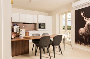 A modern kitchen with white cabinets, a wooden island, and a dining area with four chairs.