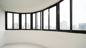 Una habitació amb una paret blanca corba i grans finestres amb estructura negra.