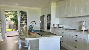 A modern kitchen with a central island, white cabinetry, a built-in oven, and a blender on the countertop.