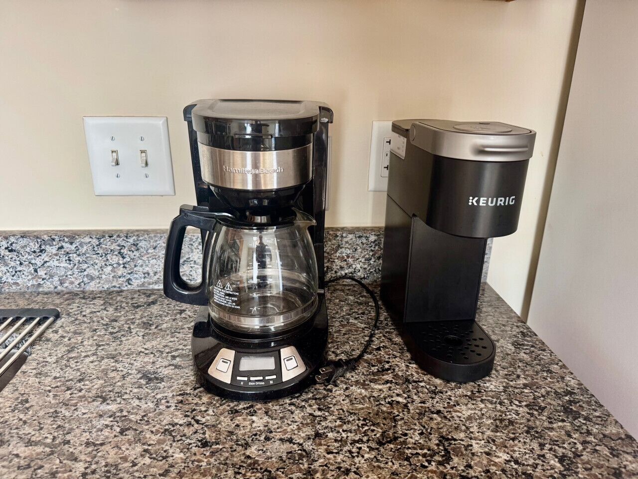 Una cafetera con jarra de vidrio y una máquina Keurig sobre una encimera de granito.