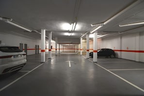 A multi-level parking garage with white pillars, orange safety lines, and directional arrows on the floor. - DARSENA A B-1 (Estartit)
