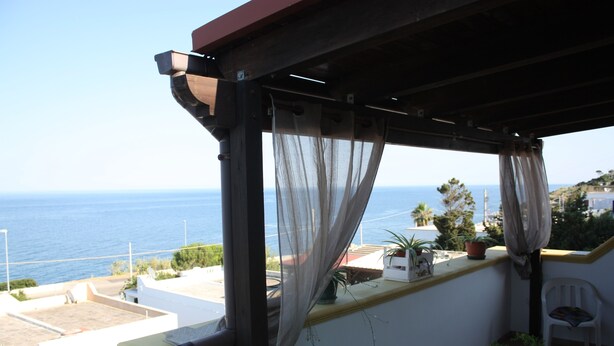 A balcony with a view of the sea, a chair, and potted plants. - Carrube House, in Andrano offers a terrace and sea views. (Marina di Andrano)