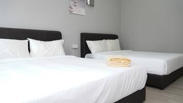 Habitación de hotel con dos camas, ropa de cama blanca, una lámpara de pared y un cartel.