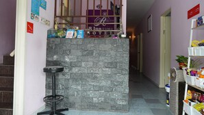 Ein Hotel-Empfangsbereich mit Steinwand, einem Barhocker und einer Rezeption.