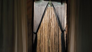 Una stanza con pavimento in legno, una finestra con tende e una parete in legno.