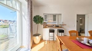 A modern kitchen with white cabinets, a wooden countertop, and a potted tree.