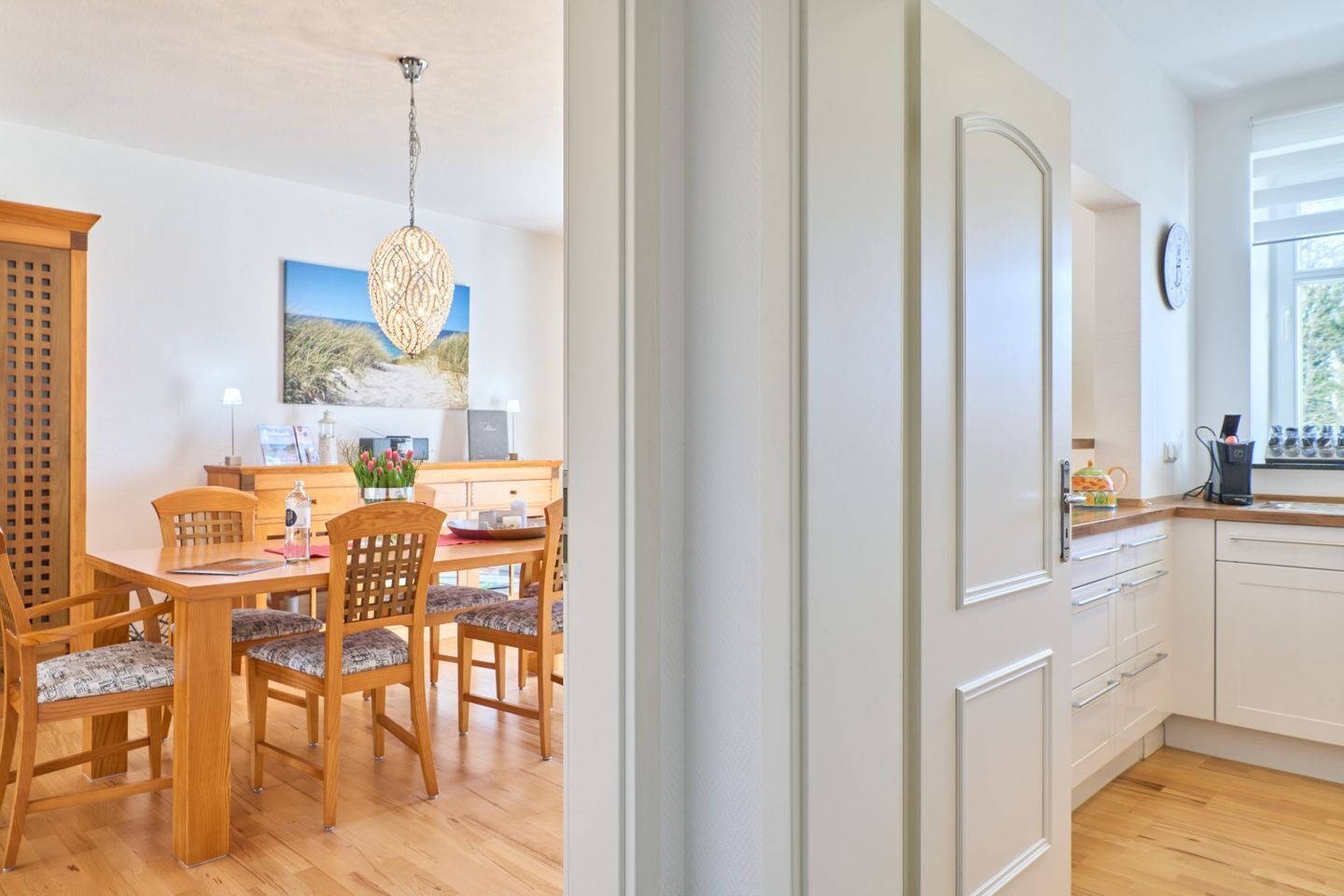 A modern kitchen with white cabinets, a wooden countertop, and a window with a view.