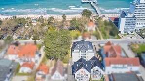 An aerial view of a coastal town with a beach, a pier, and residential buildings.