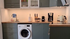 Eine kleine Küche mit Waschmaschine, Kaffeemaschine und Toaster.
