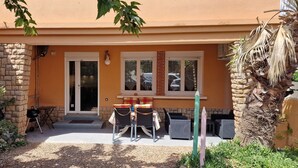 Ein Gebäude mit einer Stein-Fassade, einem Glastür-Eingang und einer kleinen Terrasse mit Gartenmöbeln.