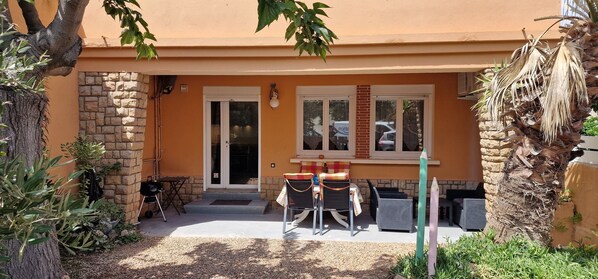 A building with a stone facade, a glass door entrance, and a small patio area with outdoor furniture.