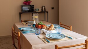 Una mesa de comedor servida con platos, cubiertos y una jarrón de agua.