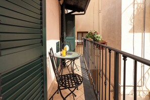 Un balcon avec une table, des chaises et des plantes en pot.