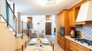 Una cocina moderna con armarios de madera, una estufa a gas y un comedor con una mesa lista para cuatro personas.