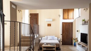 Un dormitorio con cama, escritorio, televisión y una escalera.