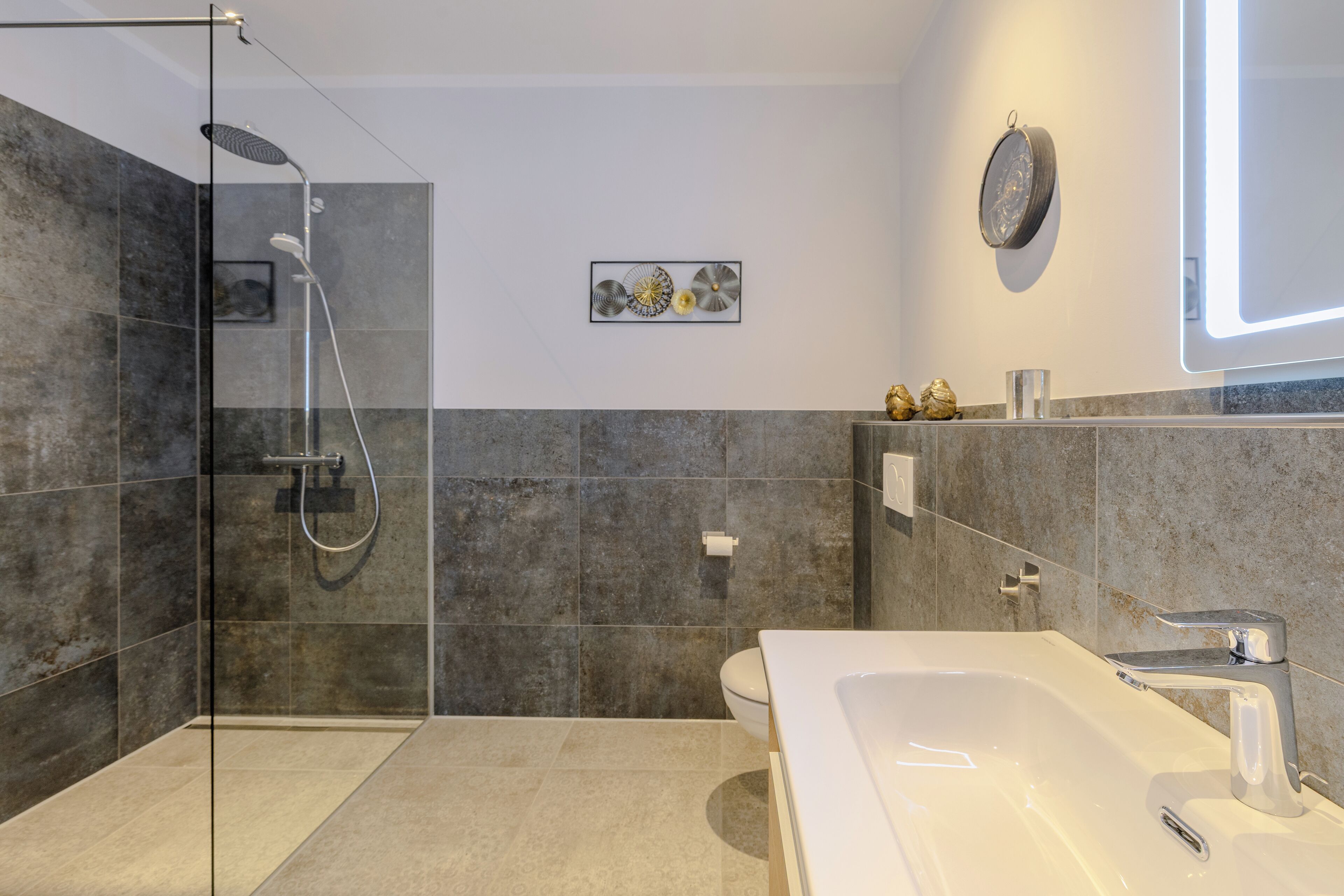 Ein modernes Badezimmer mit einer gläsernen Duschkabine, einer großen Badewanne und einer Toilette.