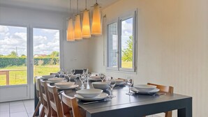 A dining area with a table set for six, chairs, and hanging pendant lights. - La Maison Bleue, on the Bay of the Somme, in a peaceful natural setting (Pendé)