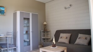 Un salon avec un canapé gris, un meuble contenant de la verrerie et une petite table sur laquelle est posé un objet décoratif.