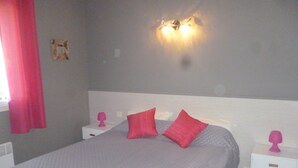 Une chambre à coucher avec un grand lit, deux tables de chevet et un luminaire fixé au mur.