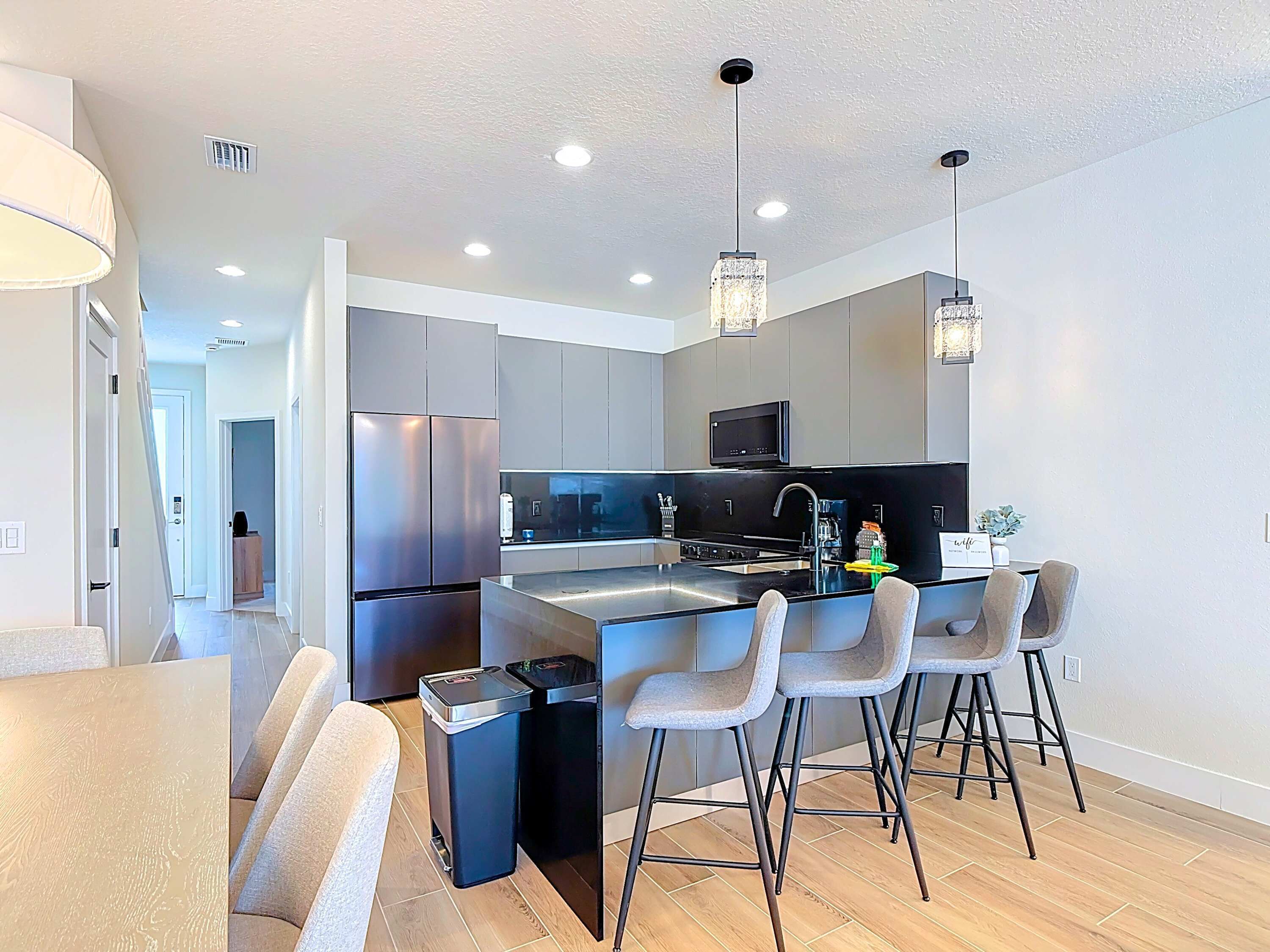 A modern kitchen with stainless steel appliances, a central island with bar stools, and pendant lighting.