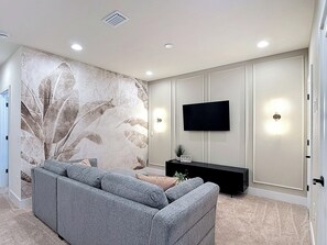 Modern media lounge with mounted TV and botanical accent wall