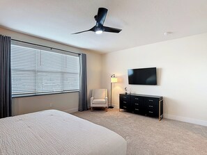 Bedroom with Wall-Mounted TV, Dresser, and Armchair