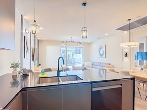 Una cocina moderna con una isla central, electrodomésticos de acero inoxidable e iluminación colgante.