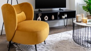 A modern living room with a yellow armchair, a black TV stand, a floor lamp, and a small round table with candles. - Bright 1BR Near Museum of London (London)