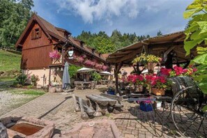A rustic wooden building with a sloped roof, a wooden bench, and a bicycle wheel. - AVALON III (Thannenkirch)