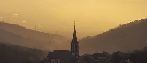 A church with a tall steeple in a valley surrounded by hills.