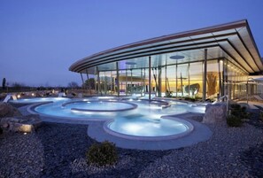 A modern building with a glass facade and a pool area with multiple hot tubs. - AVALON III (Thannenkirch)
