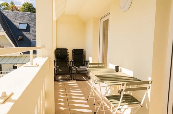 A balcony with a folding chair, a small table, and a drying rack.