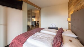 Ein Schlafzimmer mit einem großen Bett, einer Holzbalkendecke und einem Spiegel.