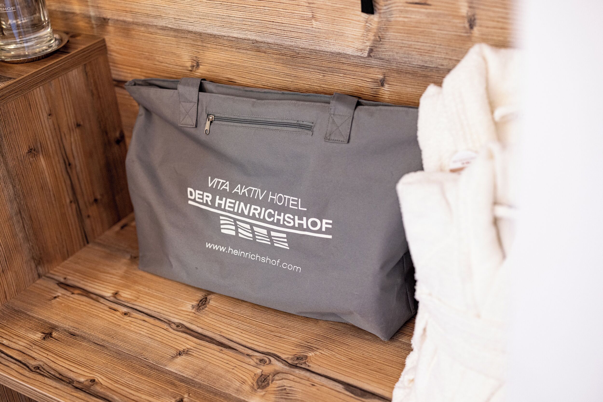 A grey tote bag with text on it placed on a wooden surface.